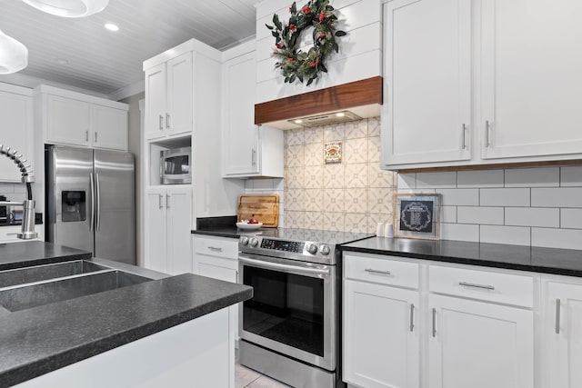 kitchen featuring decorative backsplash, appliances with stainless steel finishes, premium range hood, and white cabinetry