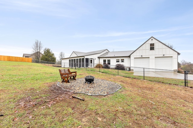 rear view of property with a lawn, an outdoor fire pit, an outdoor structure, and a garage