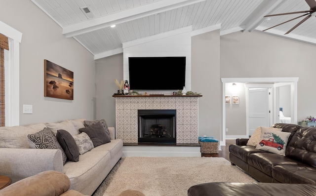 living room with wood ceiling, hardwood / wood-style flooring, ceiling fan, a tiled fireplace, and vaulted ceiling with beams