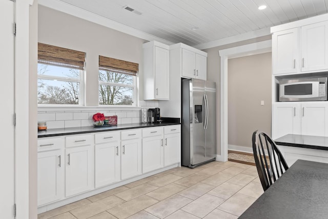 kitchen with stainless steel refrigerator with ice dispenser, decorative backsplash, white microwave, white cabinets, and wooden ceiling