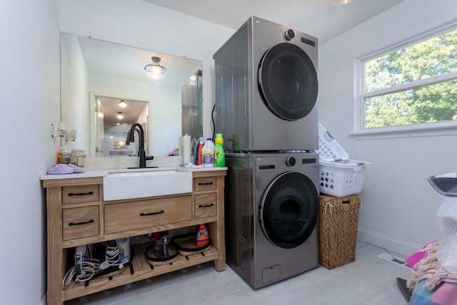 washroom with sink, light tile patterned floors, and stacked washer and dryer