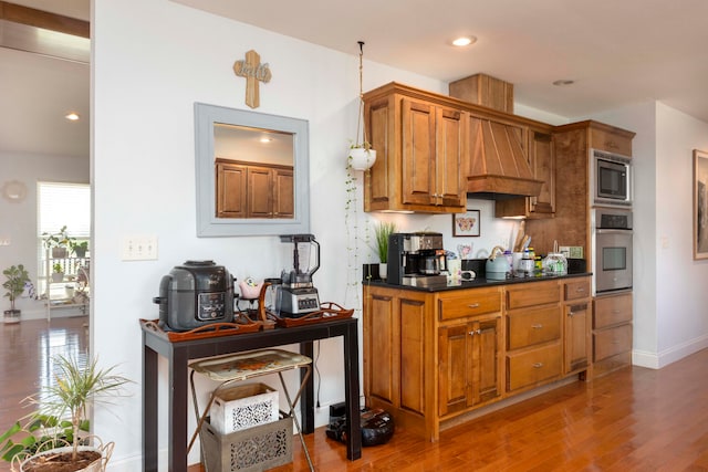 kitchen featuring wood-type flooring, stainless steel appliances, and custom exhaust hood