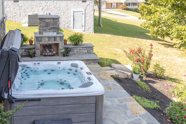 view of patio / terrace featuring central AC unit, an outdoor stone fireplace, and a hot tub