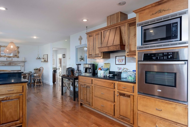 kitchen with light hardwood / wood-style floors, custom range hood, and appliances with stainless steel finishes