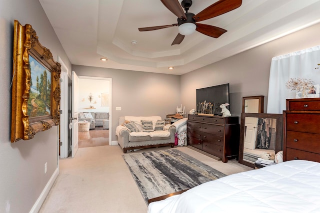 carpeted bedroom with ceiling fan and a raised ceiling