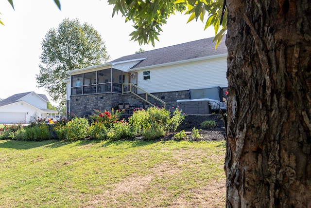 rear view of house featuring a lawn and a sunroom