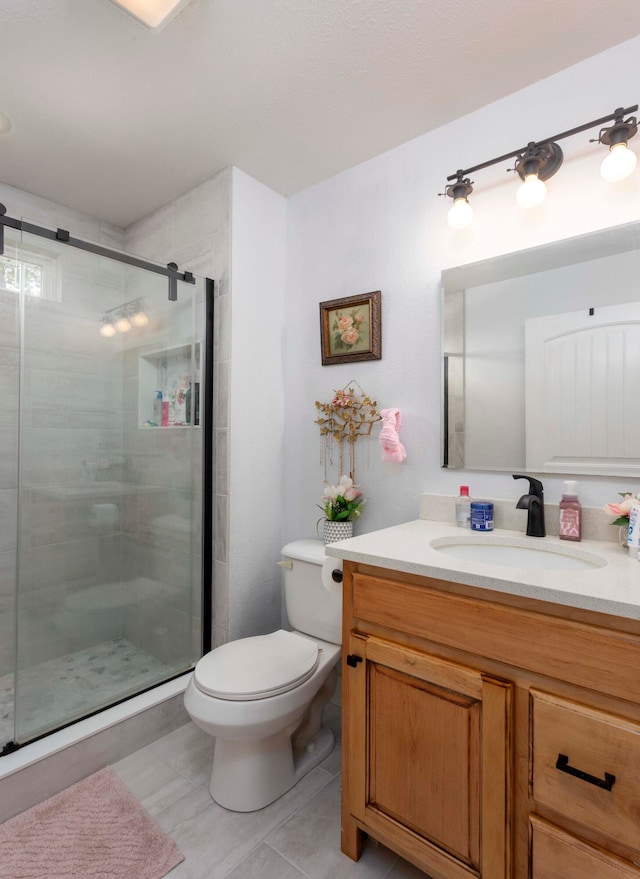 bathroom with tile patterned flooring, vanity, toilet, and walk in shower