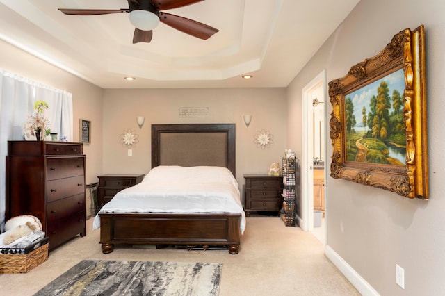 carpeted bedroom with ceiling fan and a raised ceiling