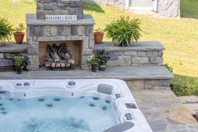 exterior space featuring an outdoor stone fireplace and a hot tub