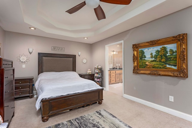 carpeted bedroom featuring connected bathroom, a raised ceiling, and ceiling fan