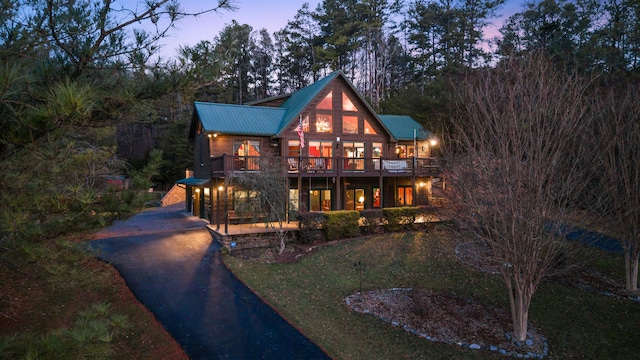 back house at dusk featuring a yard and a balcony