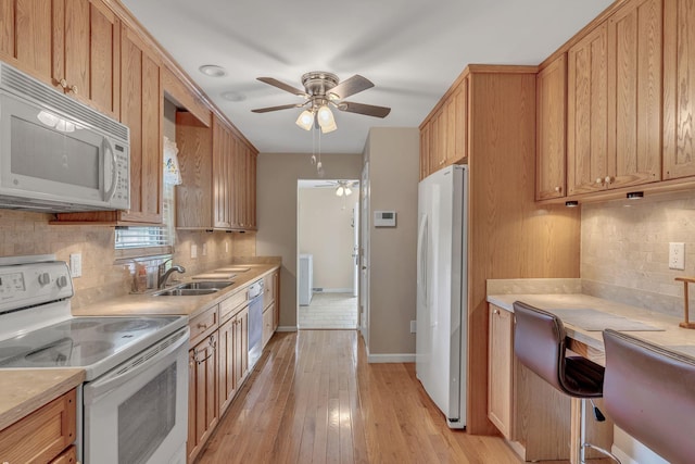 kitchen featuring decorative backsplash, white appliances, ceiling fan, sink, and light hardwood / wood-style floors