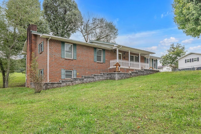 rear view of property featuring a yard and covered porch