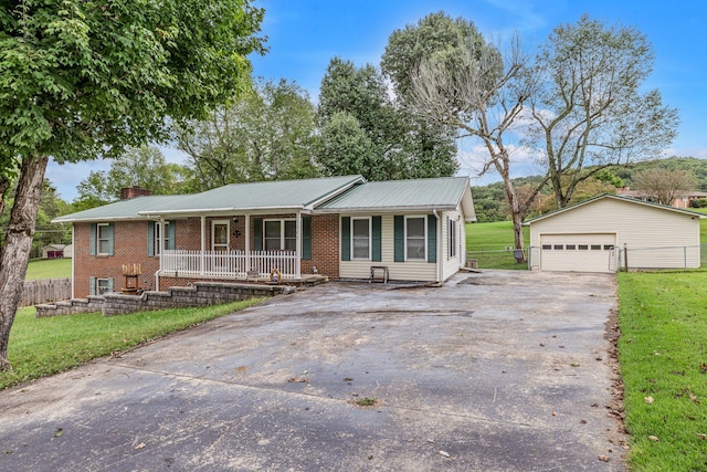 ranch-style home with a porch, a garage, an outbuilding, and a front yard