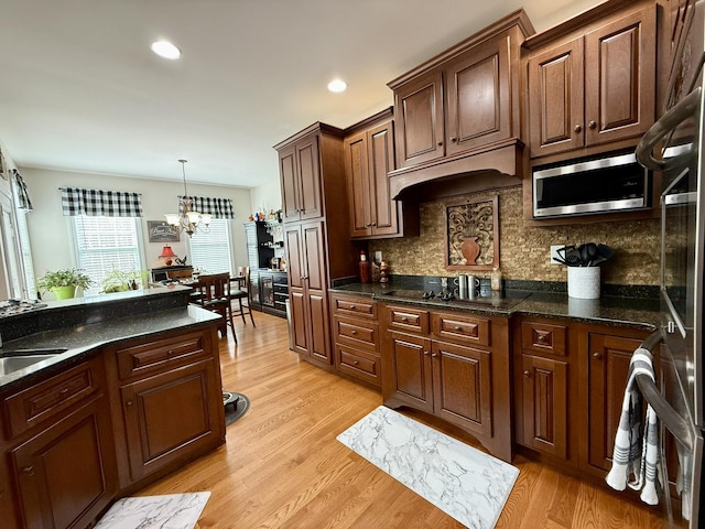 kitchen with black electric cooktop, refrigerator, custom exhaust hood, and light wood-type flooring