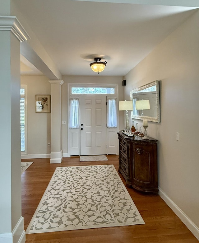 foyer entrance with ornate columns and dark hardwood / wood-style floors