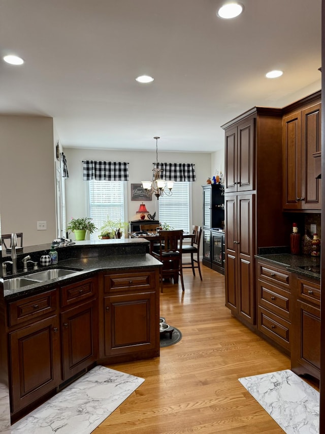 kitchen featuring pendant lighting, sink, light wood-type flooring, dark brown cabinetry, and an inviting chandelier