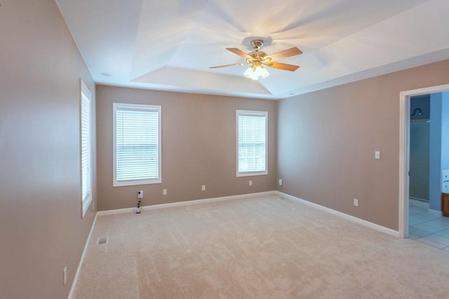 carpeted spare room featuring ceiling fan and a tray ceiling