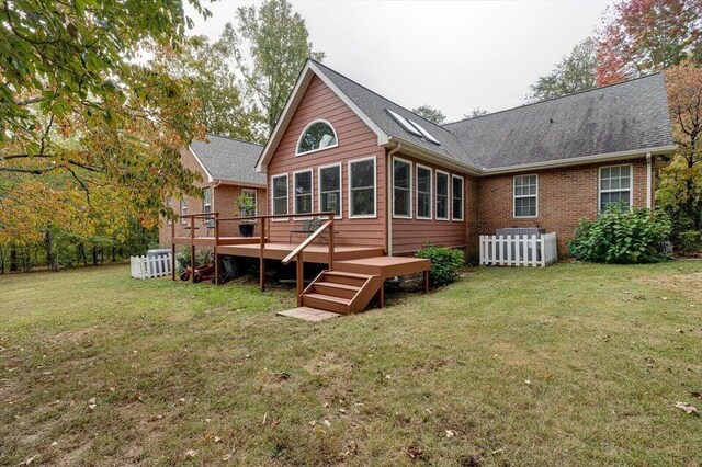 rear view of house featuring a lawn and a wooden deck