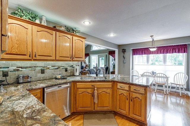 kitchen featuring sink, hanging light fixtures, light hardwood / wood-style flooring, stainless steel dishwasher, and kitchen peninsula