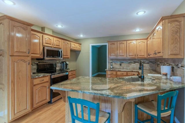 kitchen featuring a kitchen bar, kitchen peninsula, sink, light hardwood / wood-style flooring, and black electric range