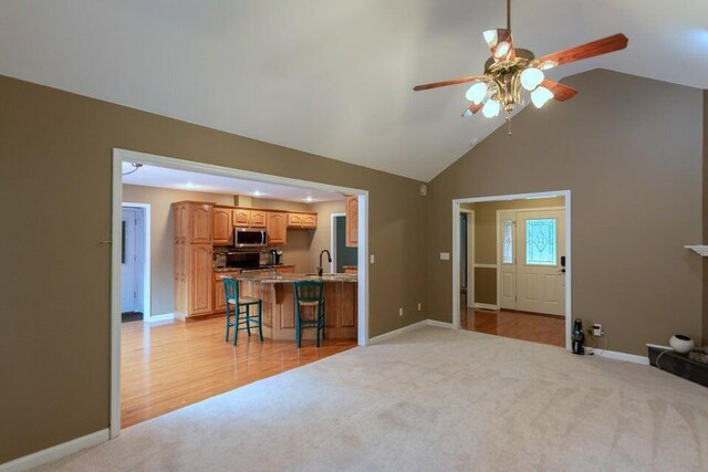 living room with light hardwood / wood-style floors, high vaulted ceiling, ceiling fan, and sink