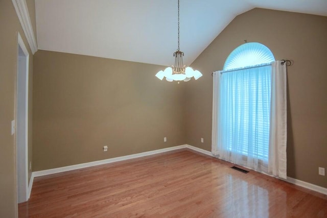 spare room featuring a chandelier, light hardwood / wood-style flooring, and vaulted ceiling