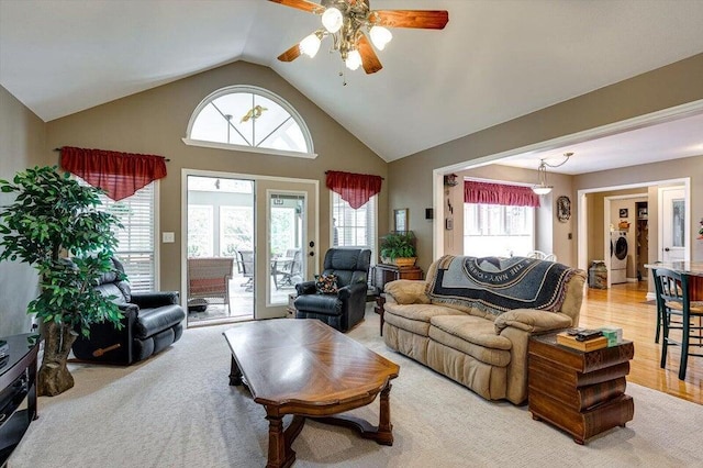 living room with ceiling fan, washer / dryer, light wood-type flooring, and high vaulted ceiling