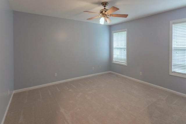 spare room with ceiling fan, carpet floors, and a wealth of natural light