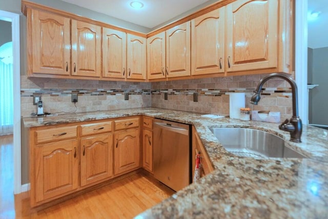 kitchen with sink, light stone counters, light hardwood / wood-style flooring, stainless steel dishwasher, and backsplash