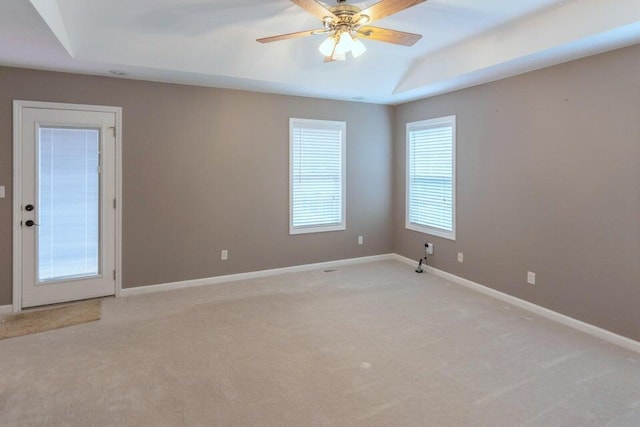 empty room featuring light colored carpet, a raised ceiling, and ceiling fan