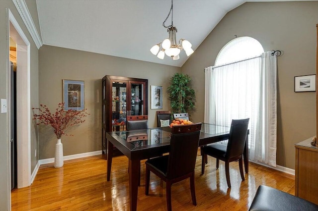 dining space with a notable chandelier, vaulted ceiling, and light wood-type flooring