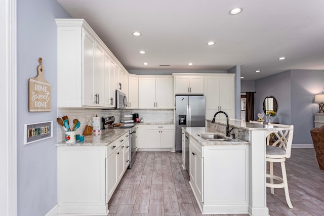 kitchen featuring white cabinets, light wood-type flooring, sink, and appliances with stainless steel finishes