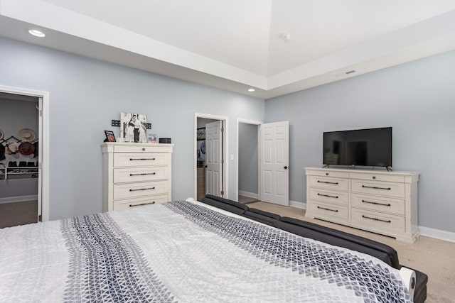 bedroom with a walk in closet, light carpet, and a closet