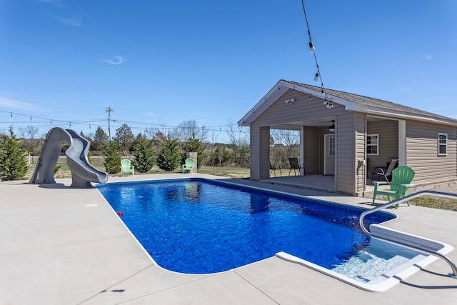 view of pool featuring an outbuilding, a patio, and a water slide