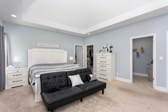 carpeted bedroom featuring a walk in closet, a tray ceiling, and a closet