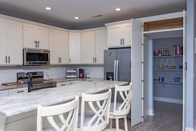 kitchen featuring a breakfast bar, stainless steel appliances, and tasteful backsplash