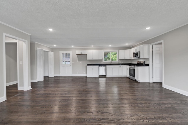 kitchen with appliances with stainless steel finishes, a textured ceiling, white cabinetry, and dark wood-type flooring