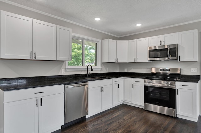 kitchen featuring appliances with stainless steel finishes, dark hardwood / wood-style flooring, a textured ceiling, crown molding, and white cabinets