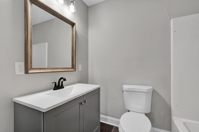 bathroom with a bathtub, vanity, a textured ceiling, and toilet