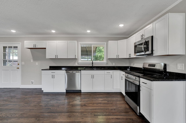 kitchen featuring dark wood-type flooring, white cabinets, stainless steel appliances, and a textured ceiling