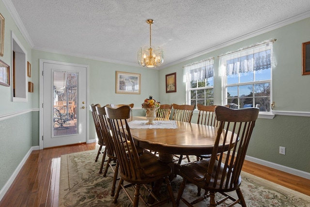 dining space with a chandelier, baseboards, hardwood / wood-style flooring, and crown molding