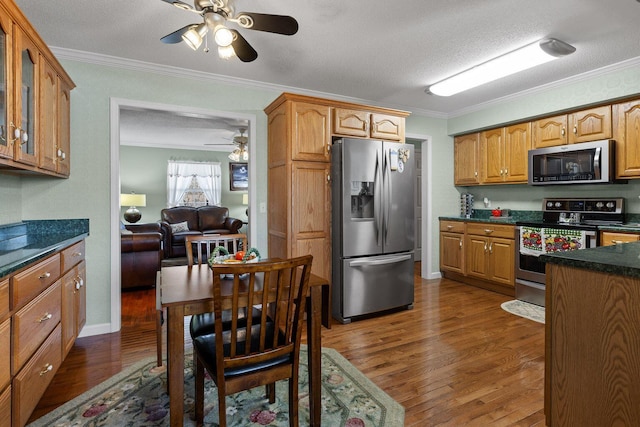 kitchen with stainless steel appliances, ornamental molding, dark wood-style flooring, and glass insert cabinets