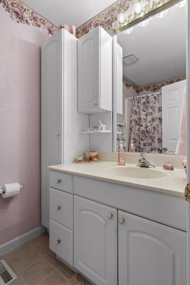 full bathroom featuring a textured ceiling, tile patterned flooring, vanity, baseboards, and wallpapered walls