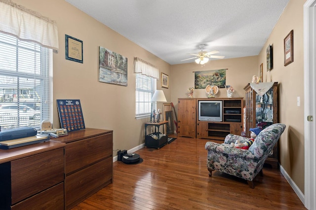 sitting room featuring a textured ceiling, ceiling fan, wood-type flooring, and baseboards