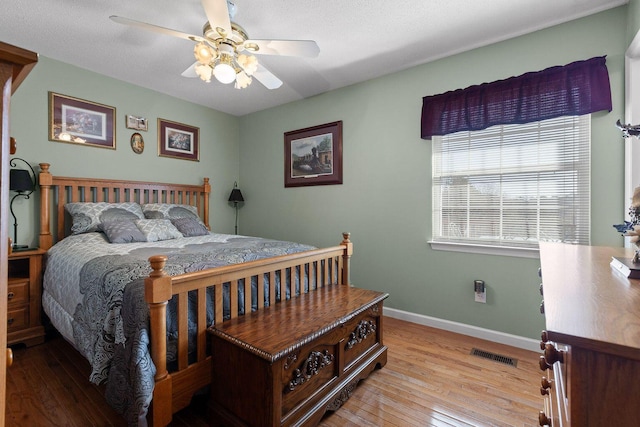 bedroom with hardwood / wood-style flooring, baseboards, visible vents, and a ceiling fan