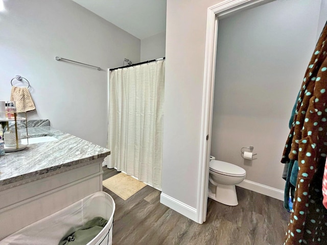 bathroom with a shower with shower curtain, toilet, wood finished floors, and baseboards