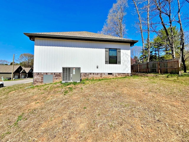 back of property with cooling unit, fence, and crawl space