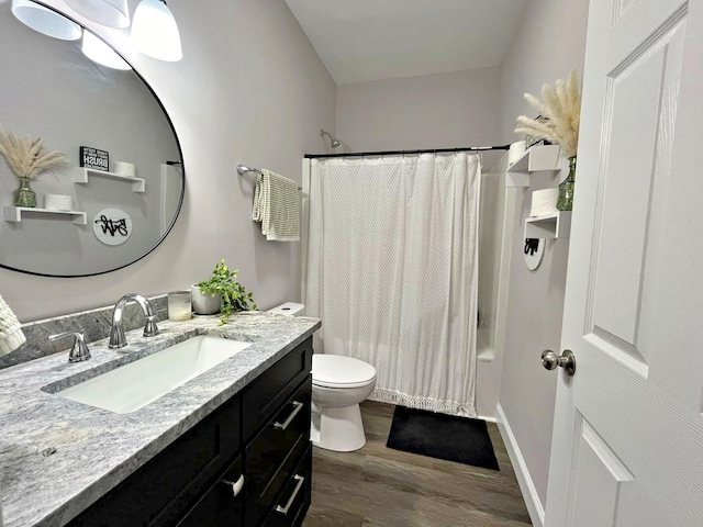 bathroom with vanity, wood finished floors, baseboards, shower / bath combo with shower curtain, and toilet