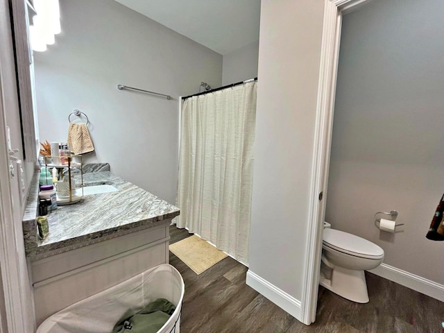 bathroom with curtained shower, toilet, baseboards, and wood finished floors